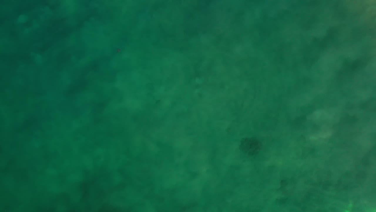 Overhead view of green ocean water with faint darker patches.
