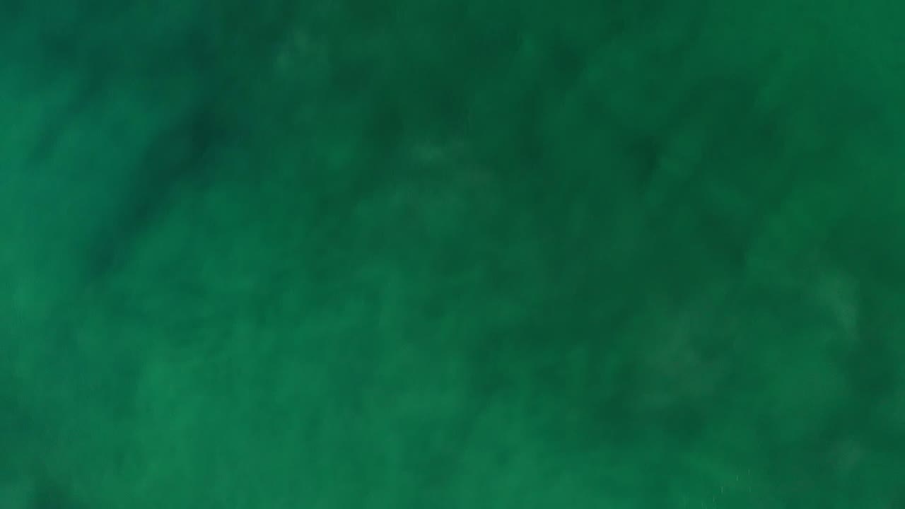 A darker green section of the Los Cabos abstract surface fills the frame, with blurred cloudy patches and no visible people.