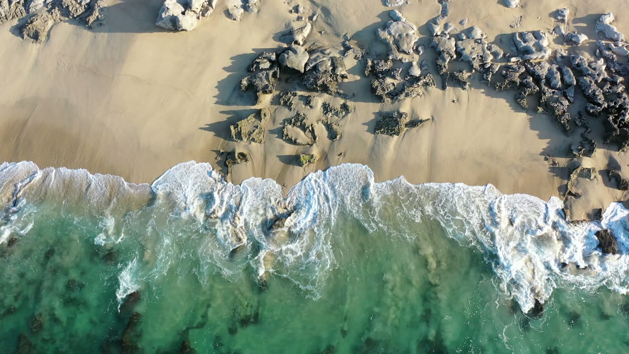 Overhead surf breaking onto a rocky sandy beach.