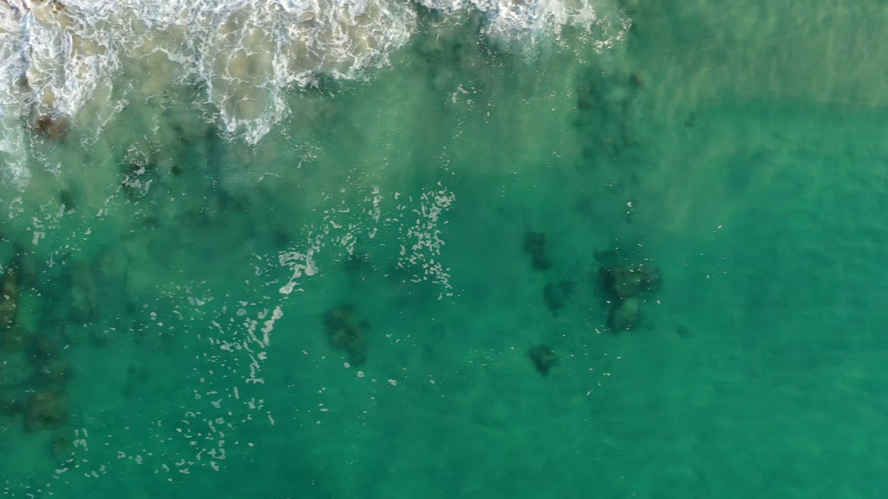 Overhead turquoise water with white surf and dark submerged patches.
