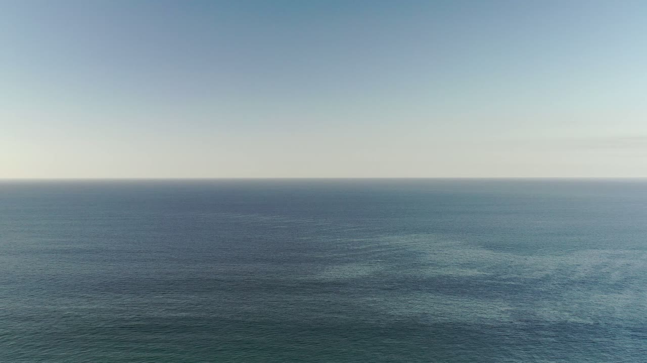 Wide Los Cabos ocean view with a pale sky band above a straight horizon and no visible people.