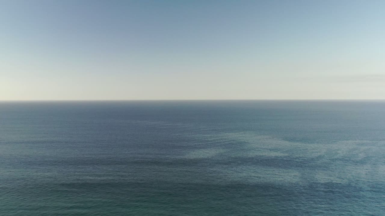 Los Cabos blue-green ocean fills most of the frame beneath a thin strip of clear sky, with no visible people or vessels.