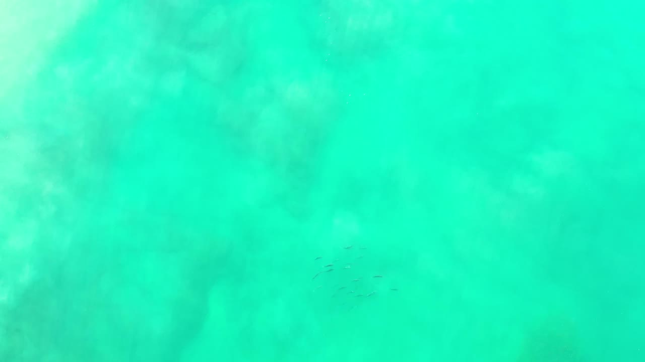 Turquoise Los Cabos underwater frame with mottled sand patterns, faint darker patches, and no visible people.