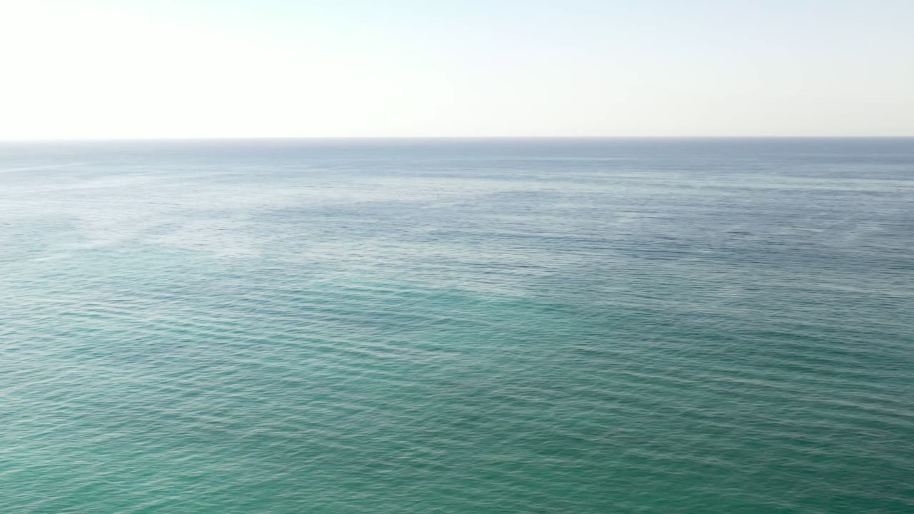 Turquoise ocean below a pale horizon.