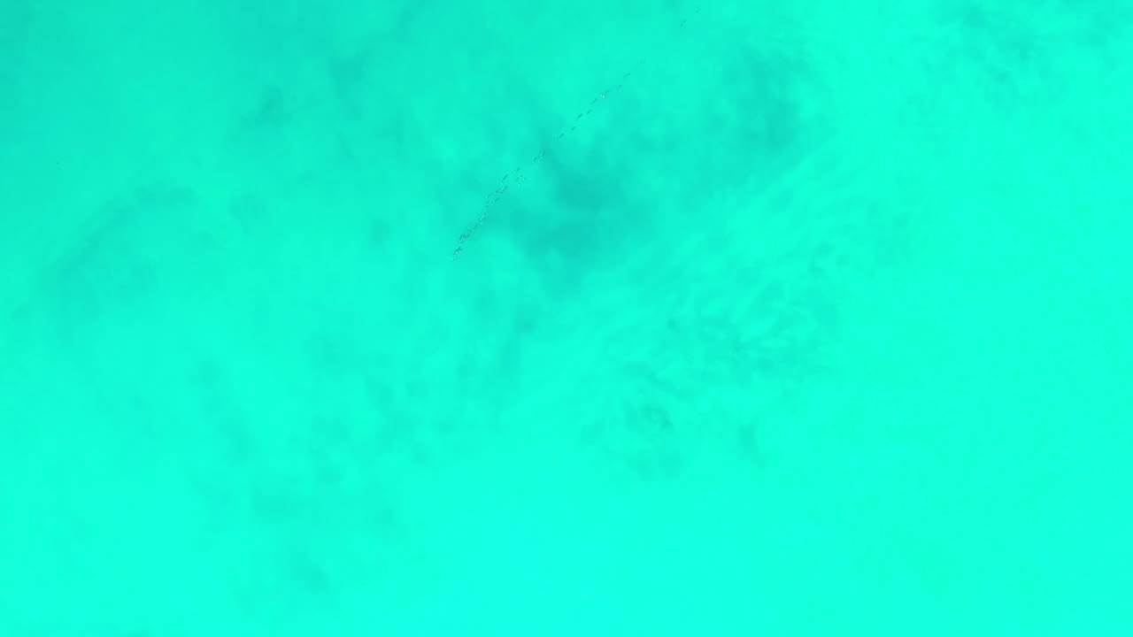 Blue-green ocean surface in Los Cabos, Mexico, seen from high above with soft mottled shading and no visible people.