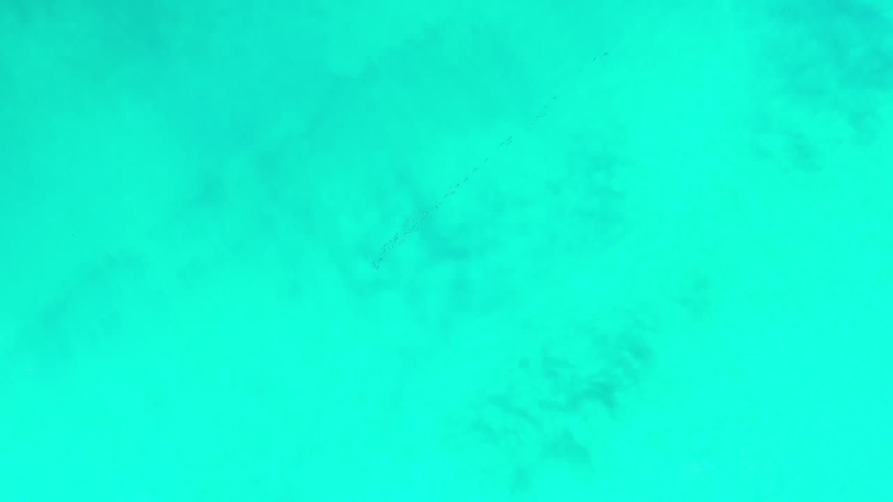 Bright turquoise water with faint darker patches beneath the surface.