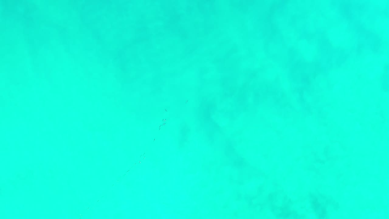 Clear turquoise water fills the frame in Los Cabos, Mexico, with darker underwater patches near the lower left and no visible people.