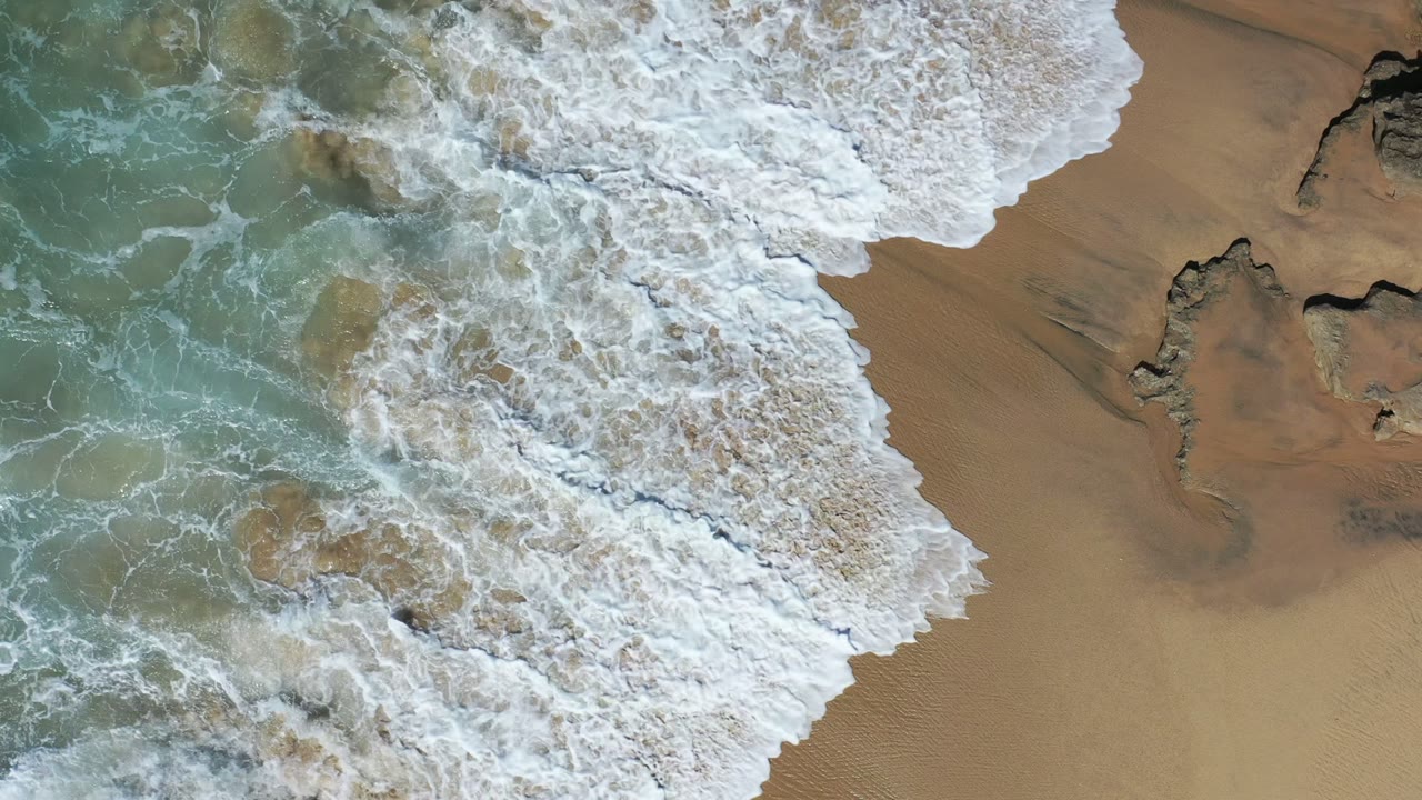 Foamy wave covers more of the beach and shallow water.