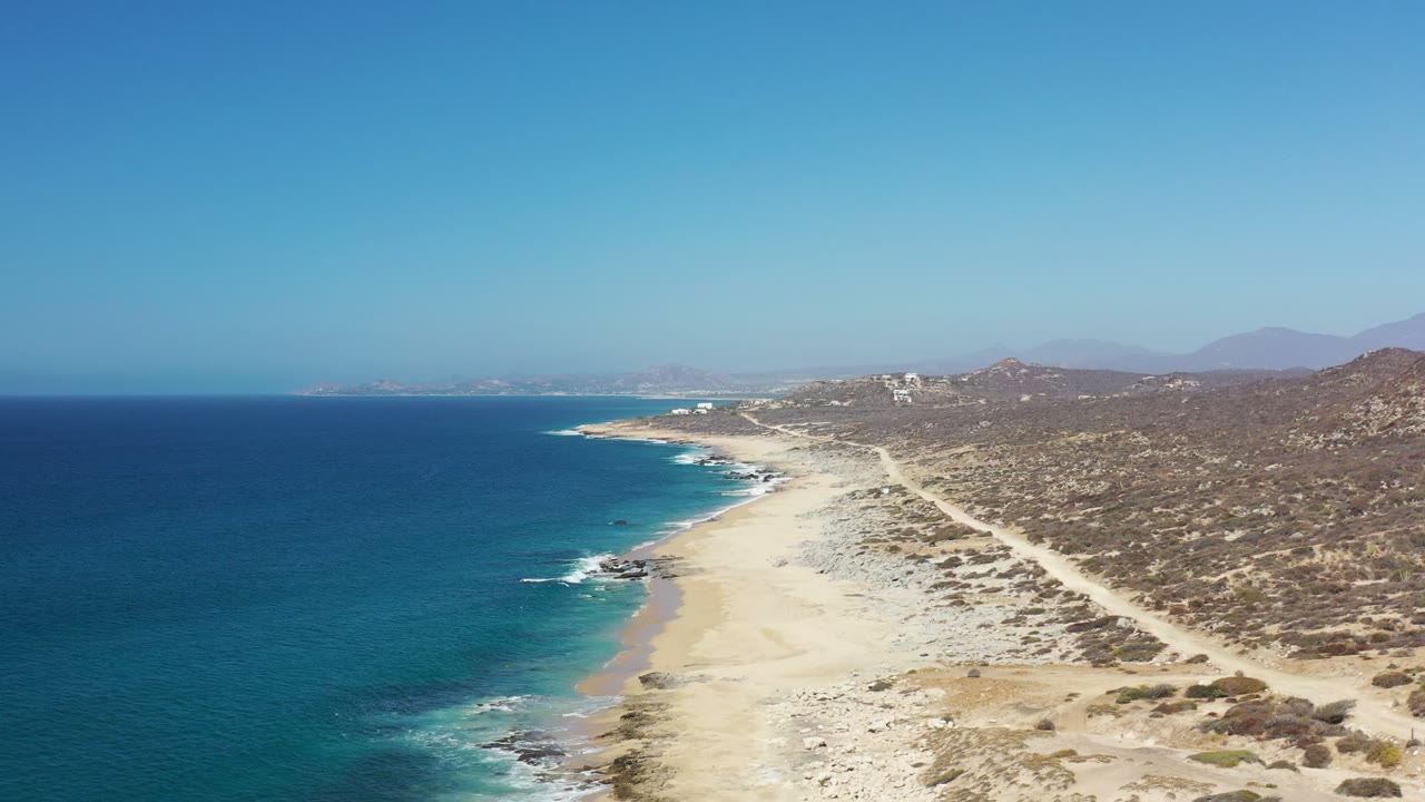 Aerial view of blue ocean beside an empty sandy coastline