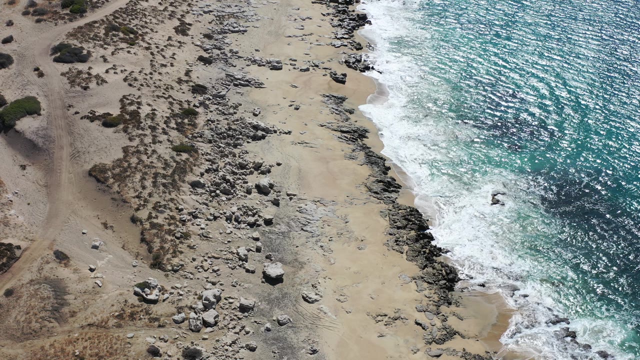 Drone view of blue sea and deserted rocky beach.