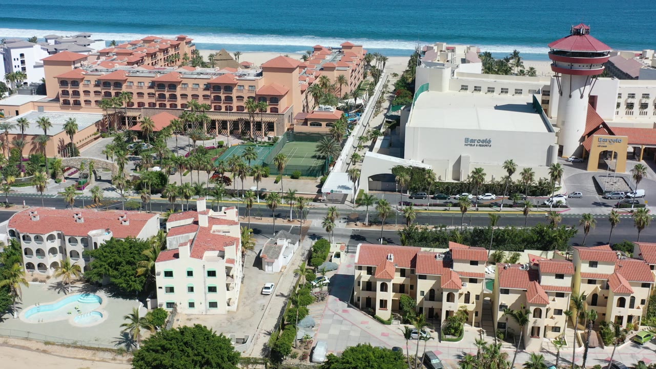 Aerial view of beachfront hotels, homes, road, palms, and ocean.
