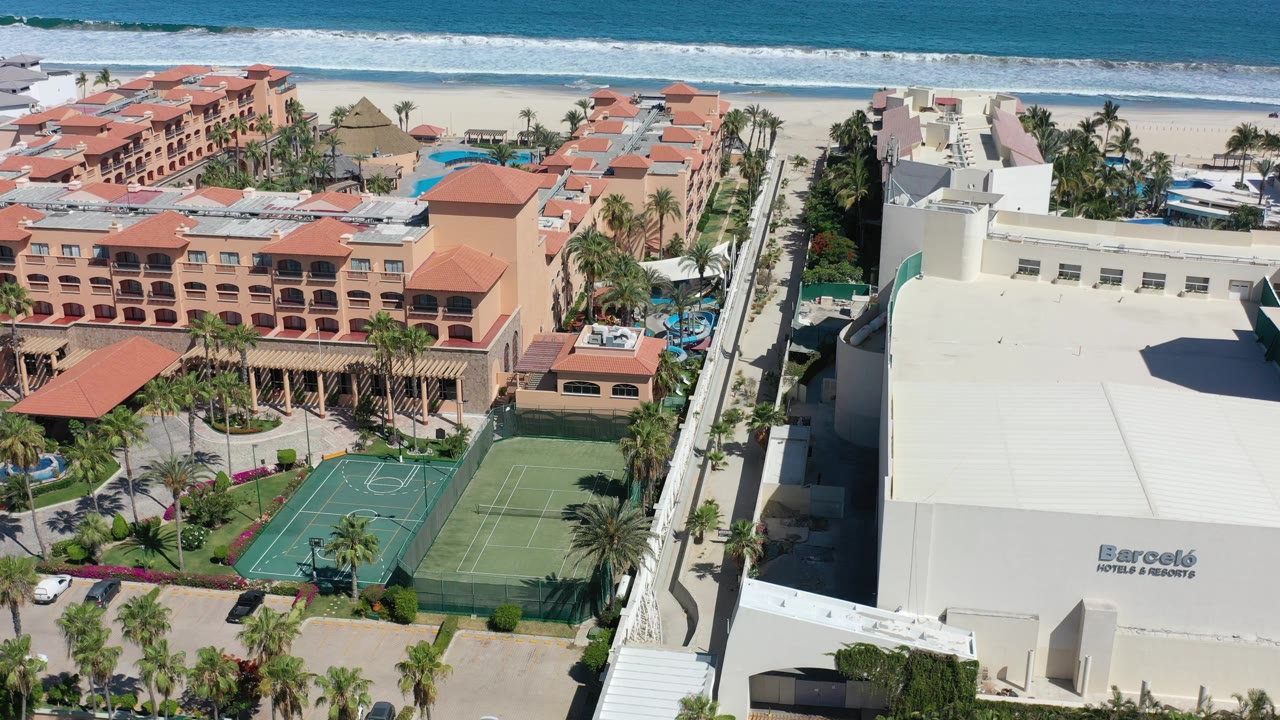 Aerial view of resort buildings beside a beach and blue ocean.