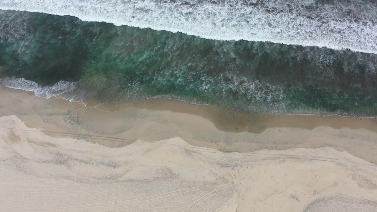 Overhead surf breaking onto pale sand.