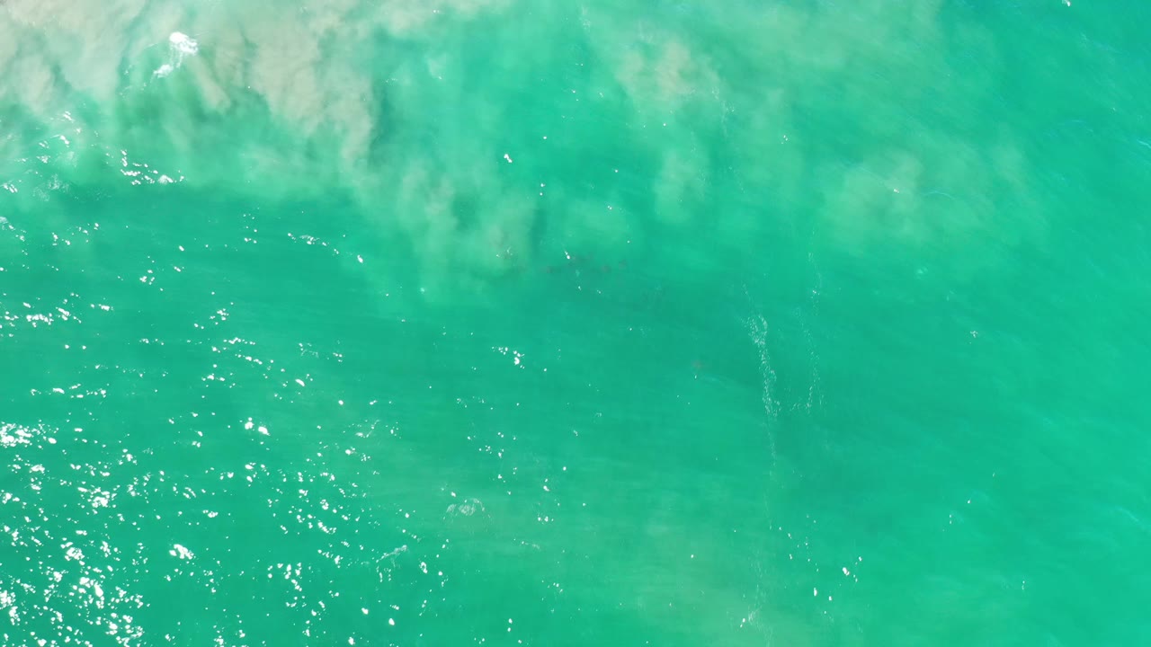 Turquoise water with cloudy reflection and darker patches below.