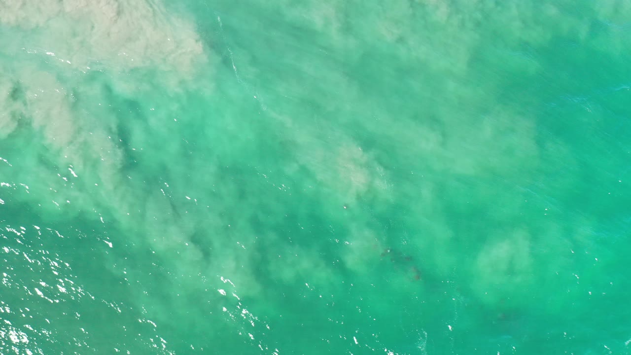 Overhead view of turquoise ocean water in Los Cabos, Mexico, with pale sandy areas under the surface and no visible people.