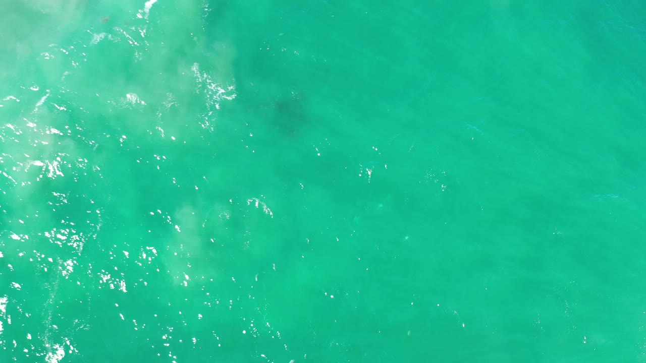 Turquoise-green water with light ripples and faint dark patches beneath.