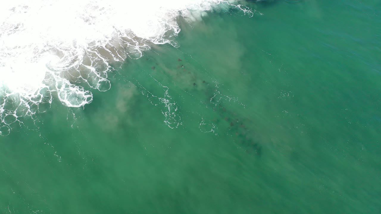 Foamy surf at the top of clear green ocean water.
