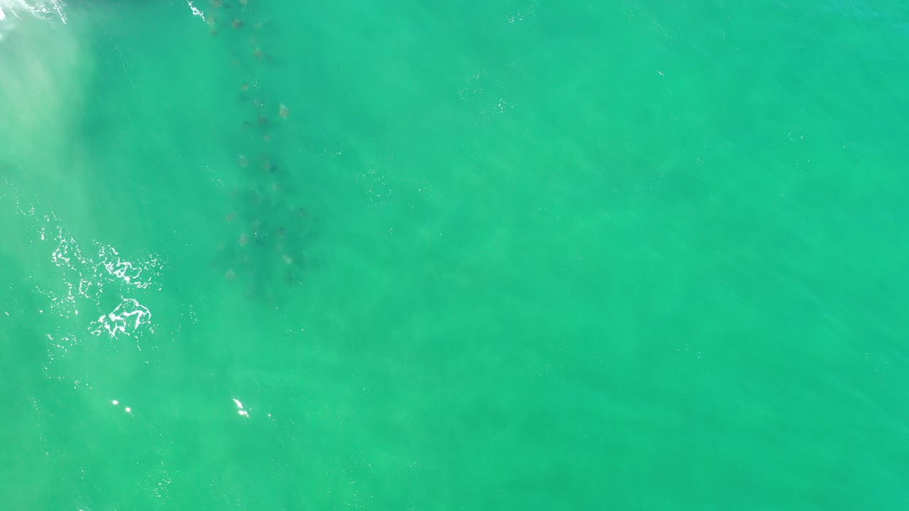 Overhead turquoise ocean water in Los Cabos, Mexico, with faint darker patches under the surface and no visible people.