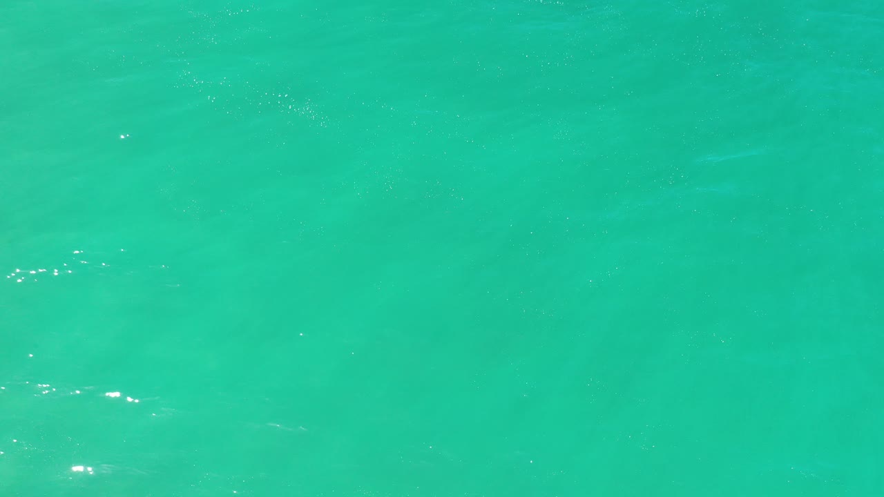 Open turquoise sea in Los Cabos, Mexico, with brighter reflective flecks across the surface and no visible shoreline or people.
