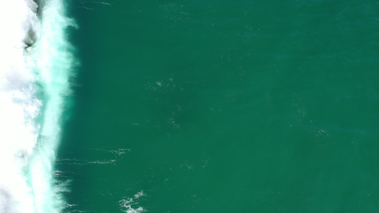 Overhead turquoise ocean with white surf along the left edge.