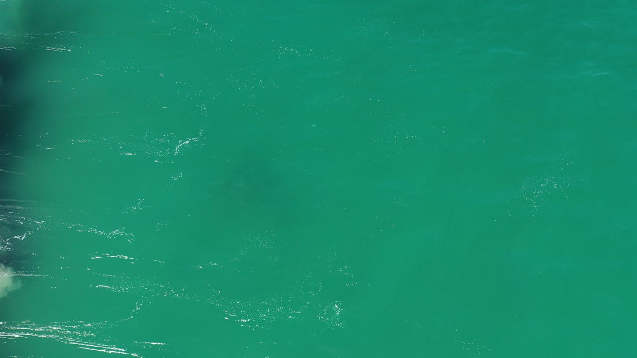 Overhead turquoise ocean with faint foam streaks.