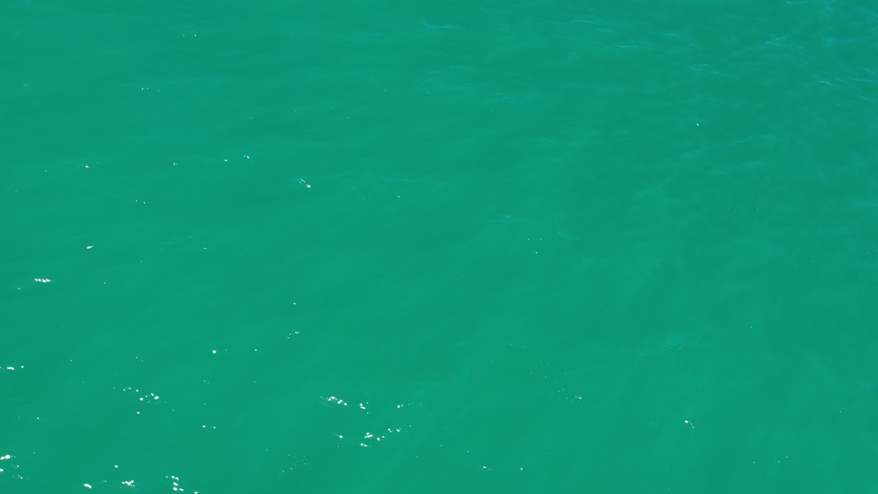 Bright green water with faint darker patches below the surface.