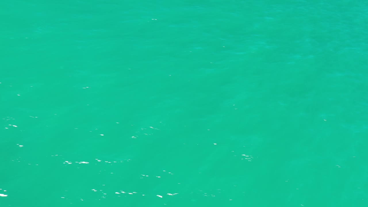 Aerial frame of Los Cabos ocean water with scattered white surface flecks and no visible people.