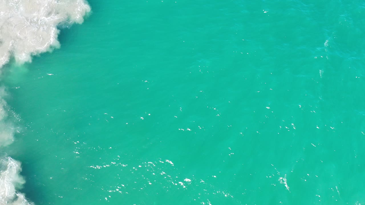 Turquoise ocean water with white foam at the left edge.