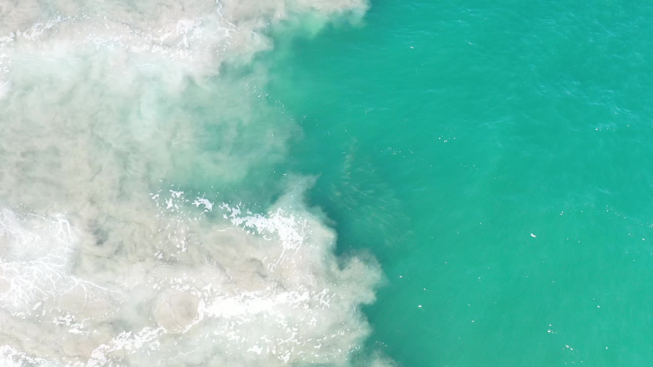 Open turquoise water with white foam at left.