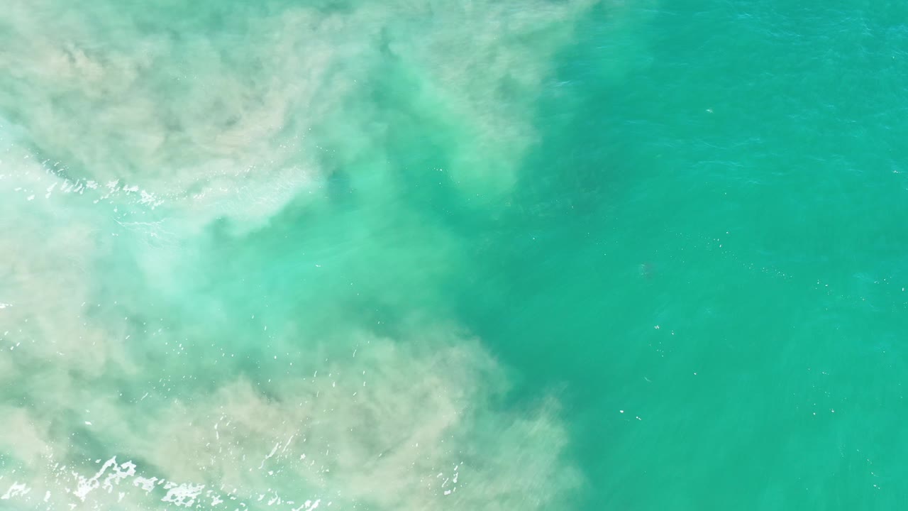 Clear turquoise water beside a pale sandy swirl.