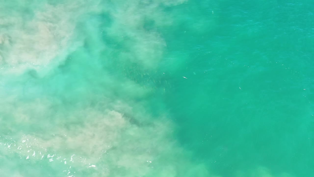 Los Cabos water surface with a pale sediment band spreading across the left side, fine wind ripples, and no visible people.