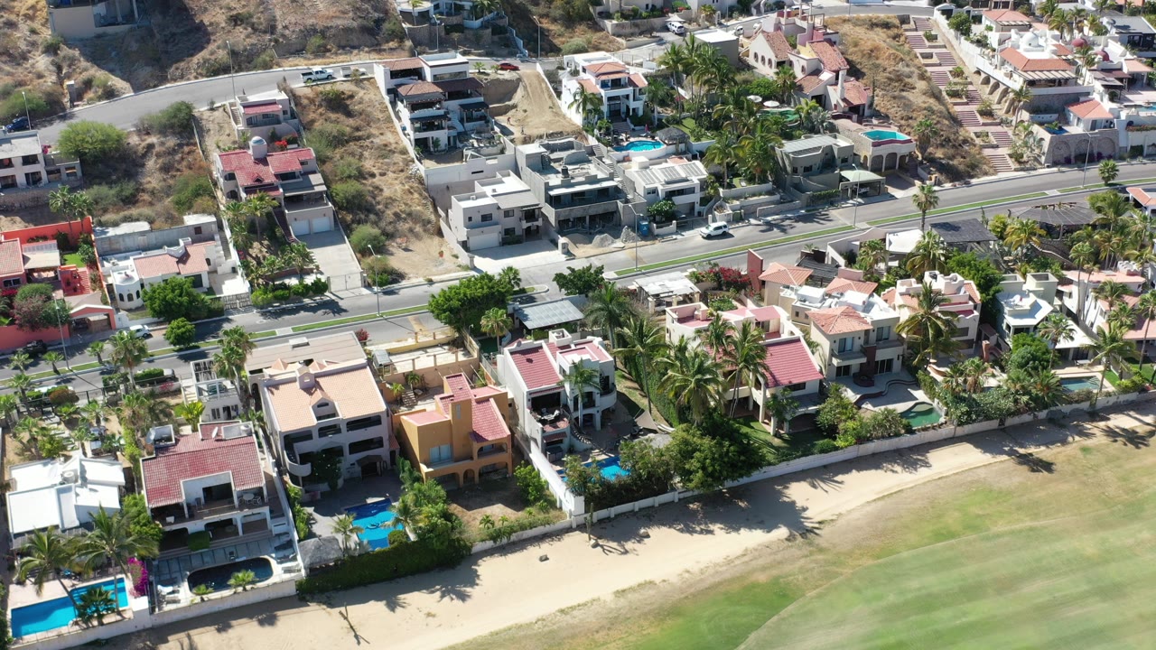 Aerial view of villas, pools, road, dry hillside, and golf-course grass.