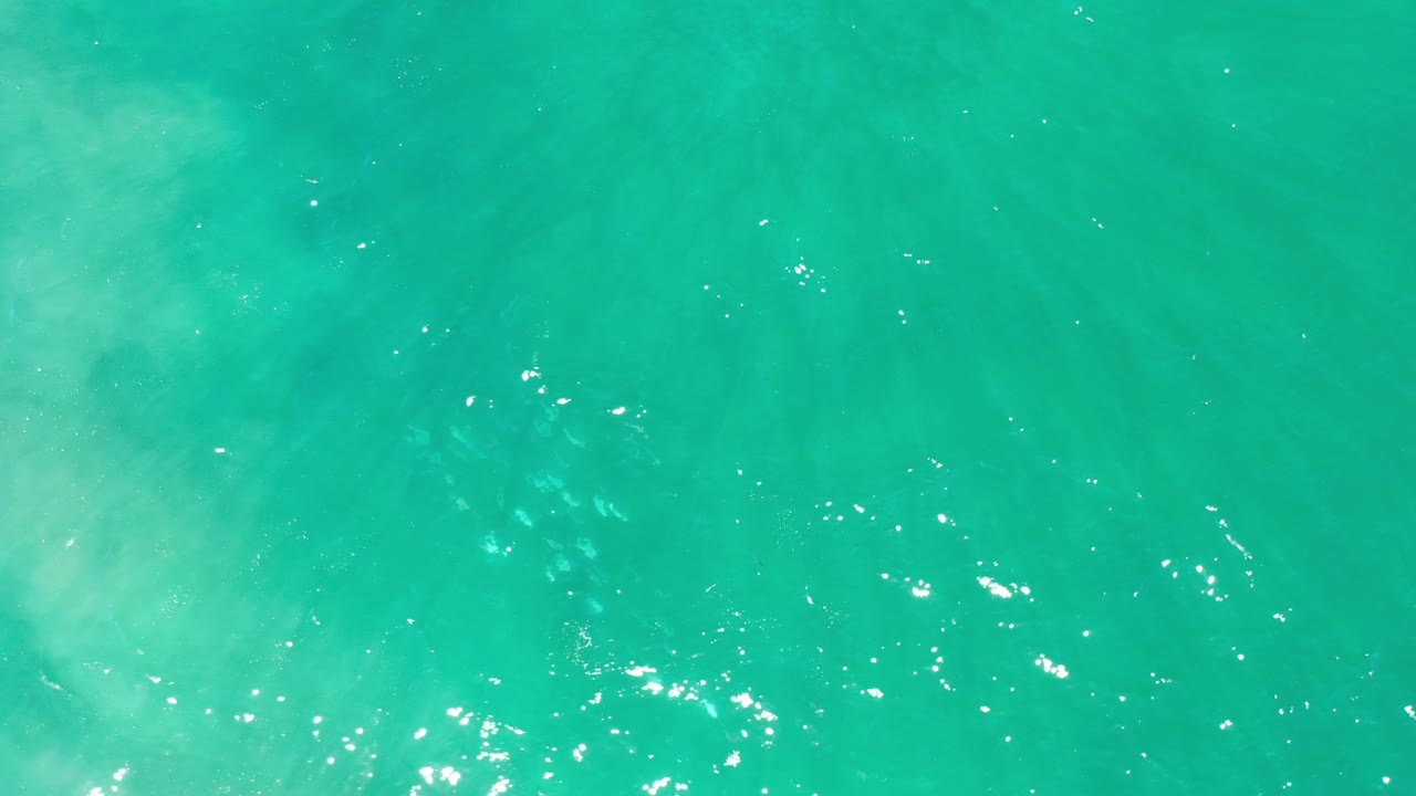 Turquoise water with a cluster of white reflections near the lower edge.