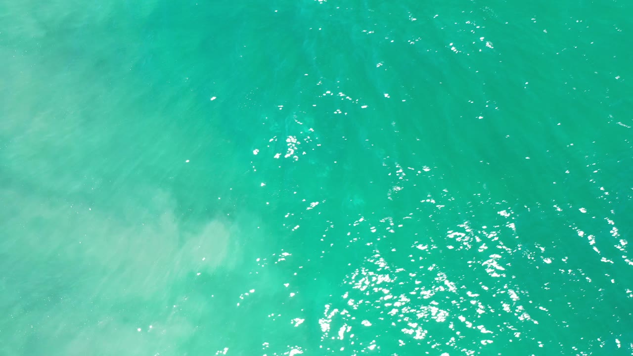 Turquoise water with bright sparkles and faint subsurface clouding