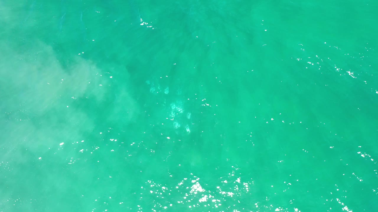 Green-blue sea surface with scattered sun glints.