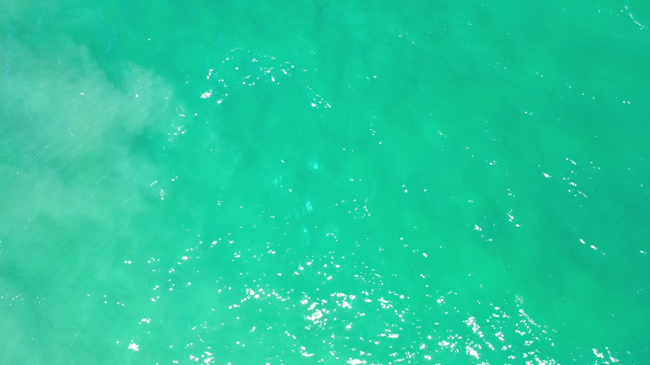 Overhead Los Cabos sea surface with fine ripples, small bright reflections, and no visible people or shoreline.