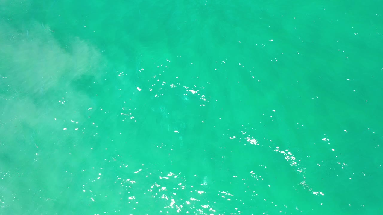 Turquoise ocean texture with a pale foam patch across the upper area.