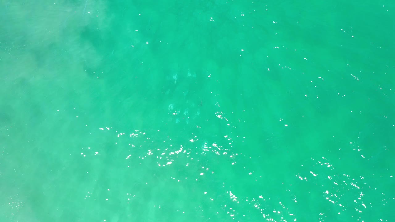 Bright turquoise water with clustered reflections near the center.