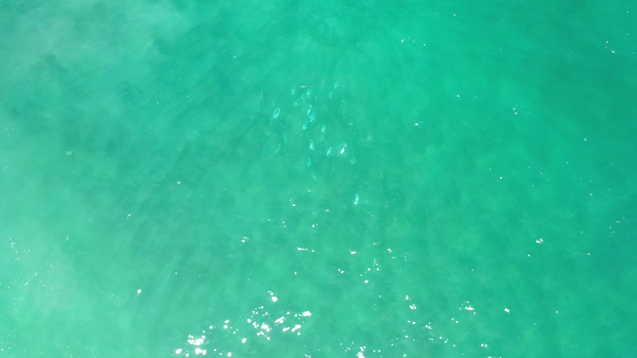 Bright aqua water with subtle darker patches and reflected light.
