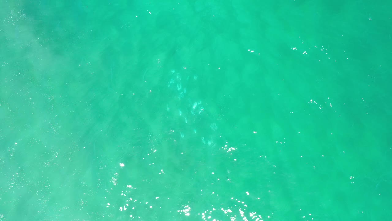 Clear aqua water fills the frame in Los Cabos, Mexico, with brighter white glints near the lower edge and no visible people.