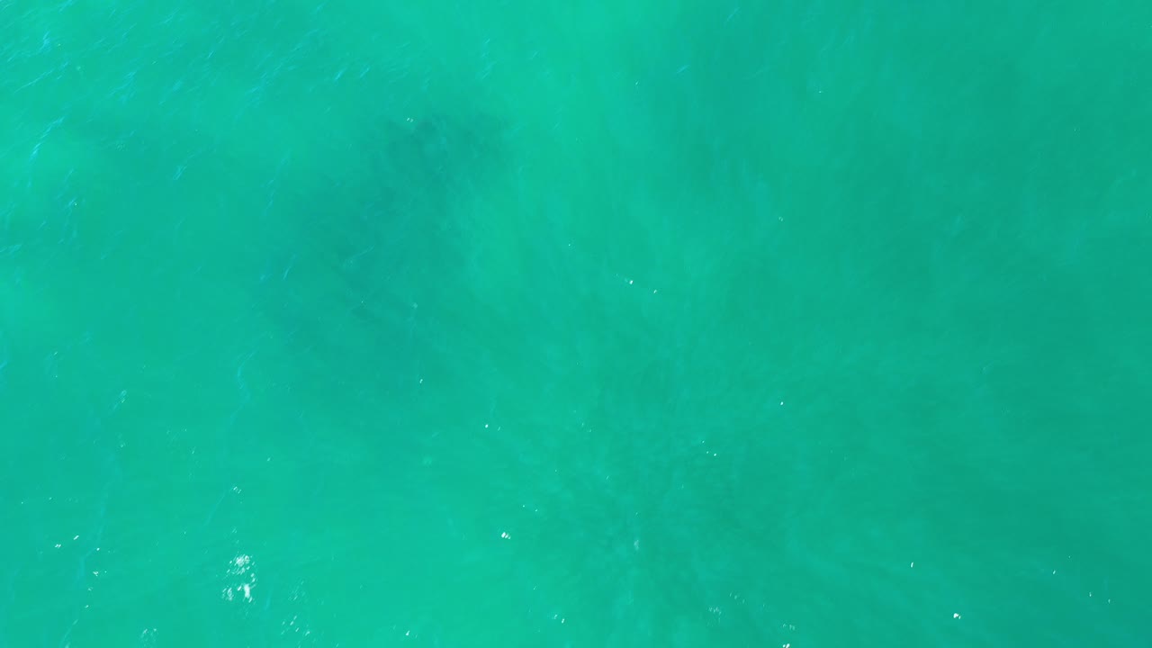 Overhead view of turquoise ocean water in Los Cabos, Mexico, with faint surface ripples, soft light variation, and no visible people.