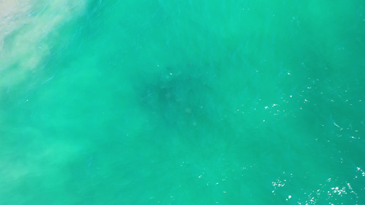 Bright teal sea with small white glints toward the right.