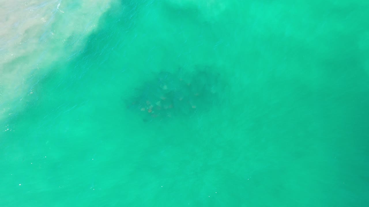 Turquoise ocean water with pale surf edge and darker patches below the surface.