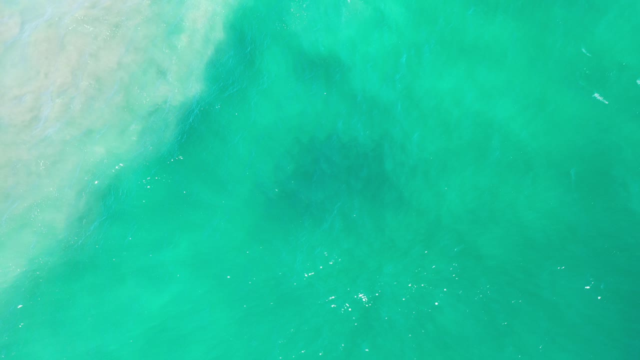 Turquoise ocean water with pale surf at the upper left.