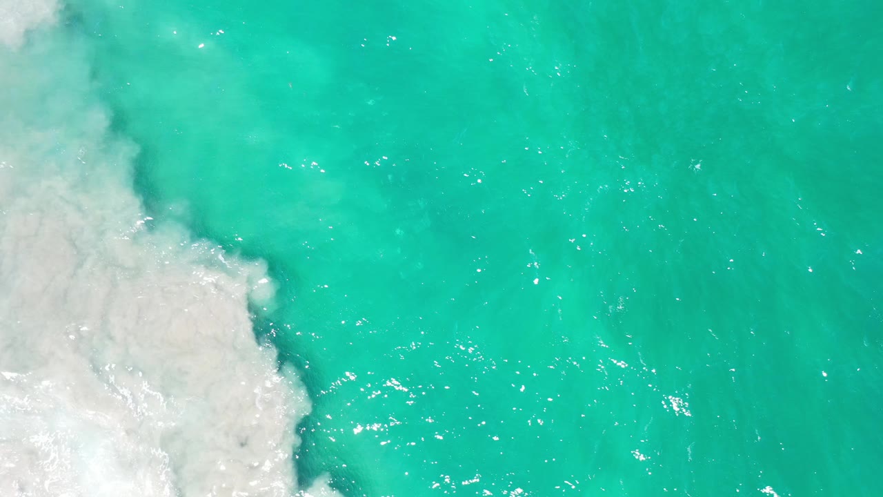 Bright teal water and pale surf edge.