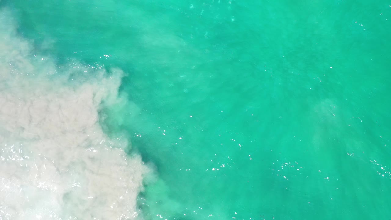 White wave foam meets turquoise water from the left.