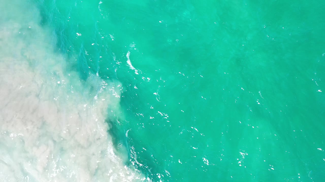 Seafoam-colored water with white surf curling in from the left.