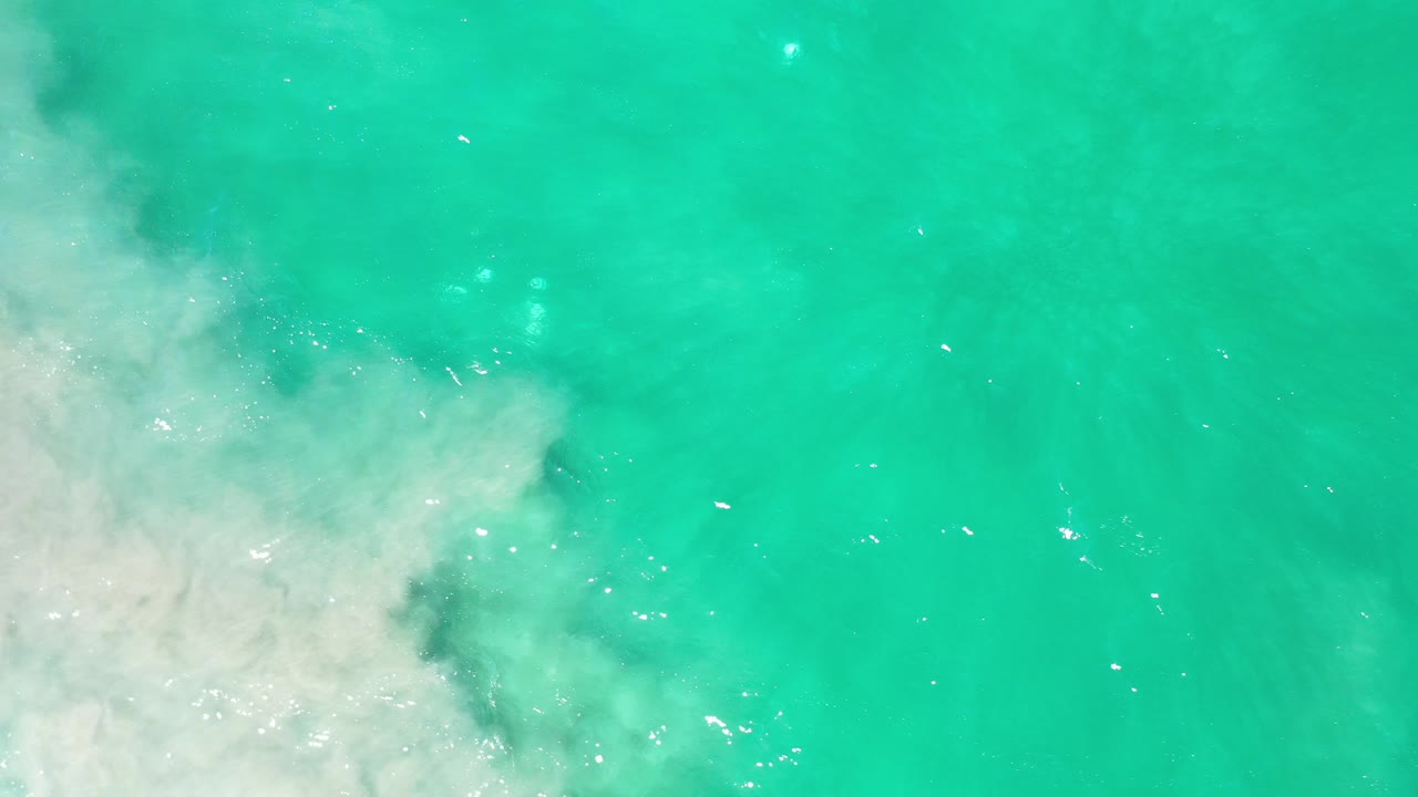 Turquoise ocean water with white surf along the left edge.