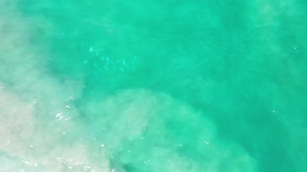 Overhead green water with pale wave wash across the lower half.
