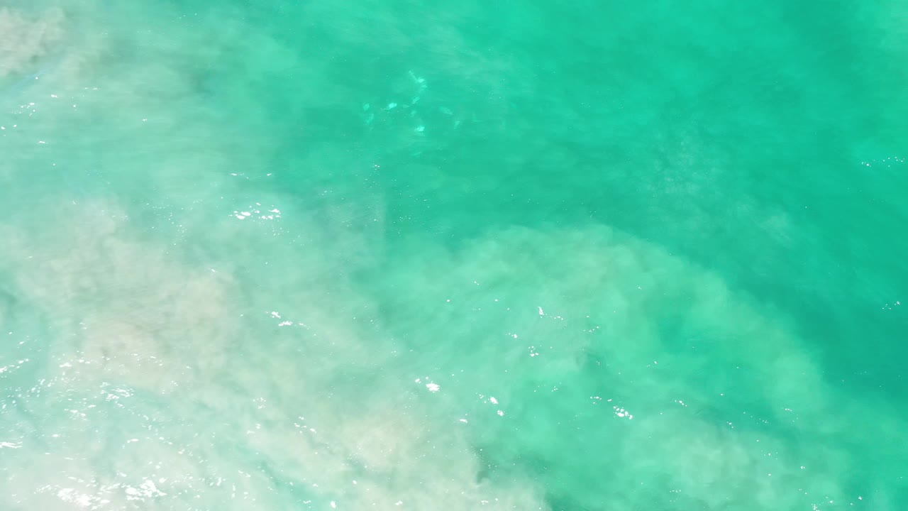 Turquoise water and milky white foam near the shoreline.